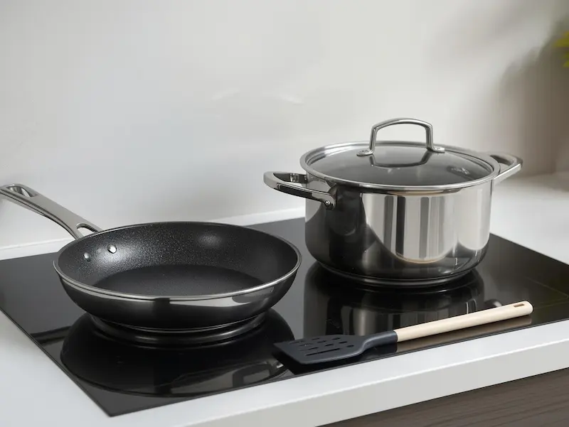Poêle antiadhésive et casserole en inox sur une plaque de cuisson
